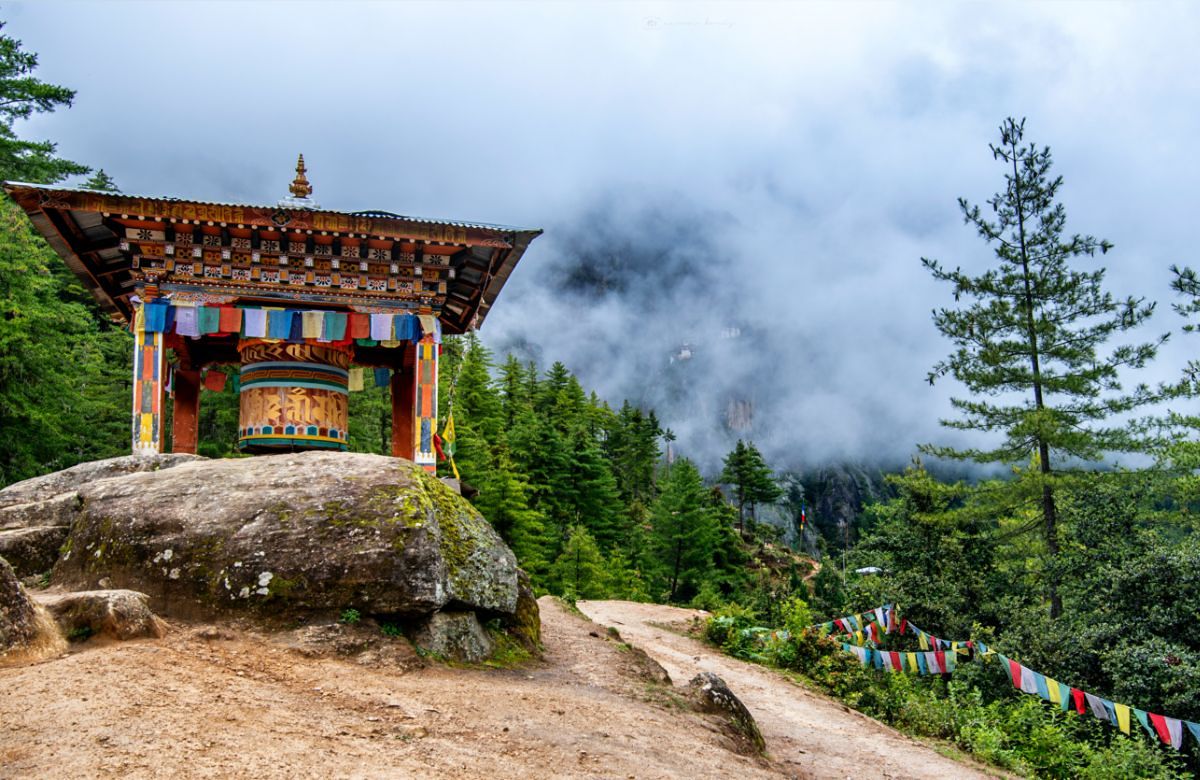 A forest gate hung with prayer flags on a Bhutanese hillside